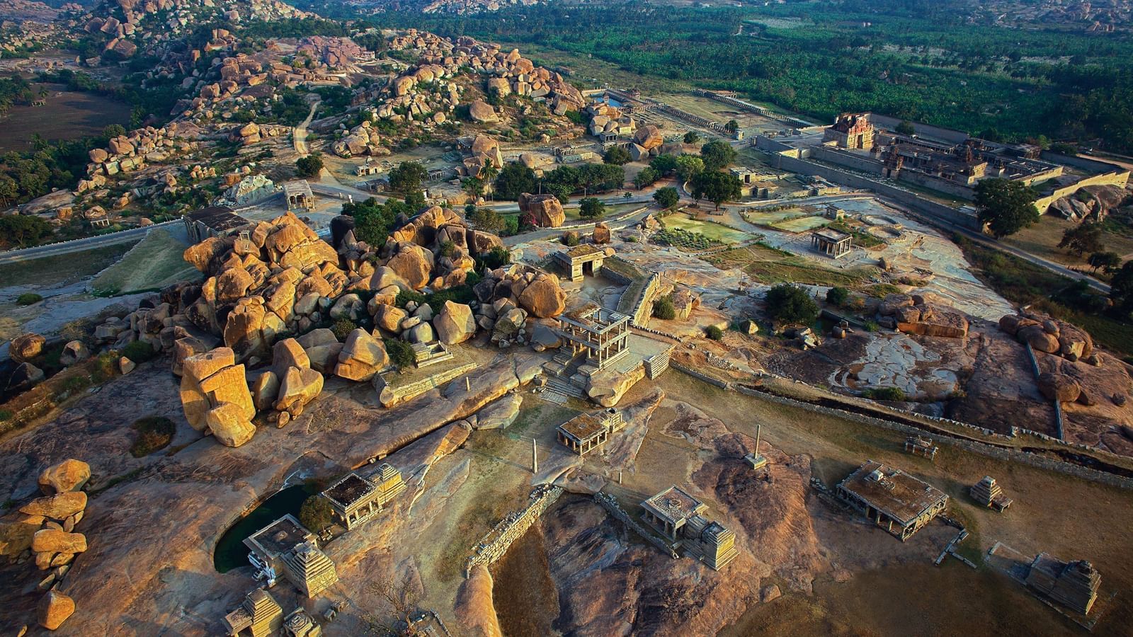 Aerial view of Hampi ruins and rocky landscape at sunset.