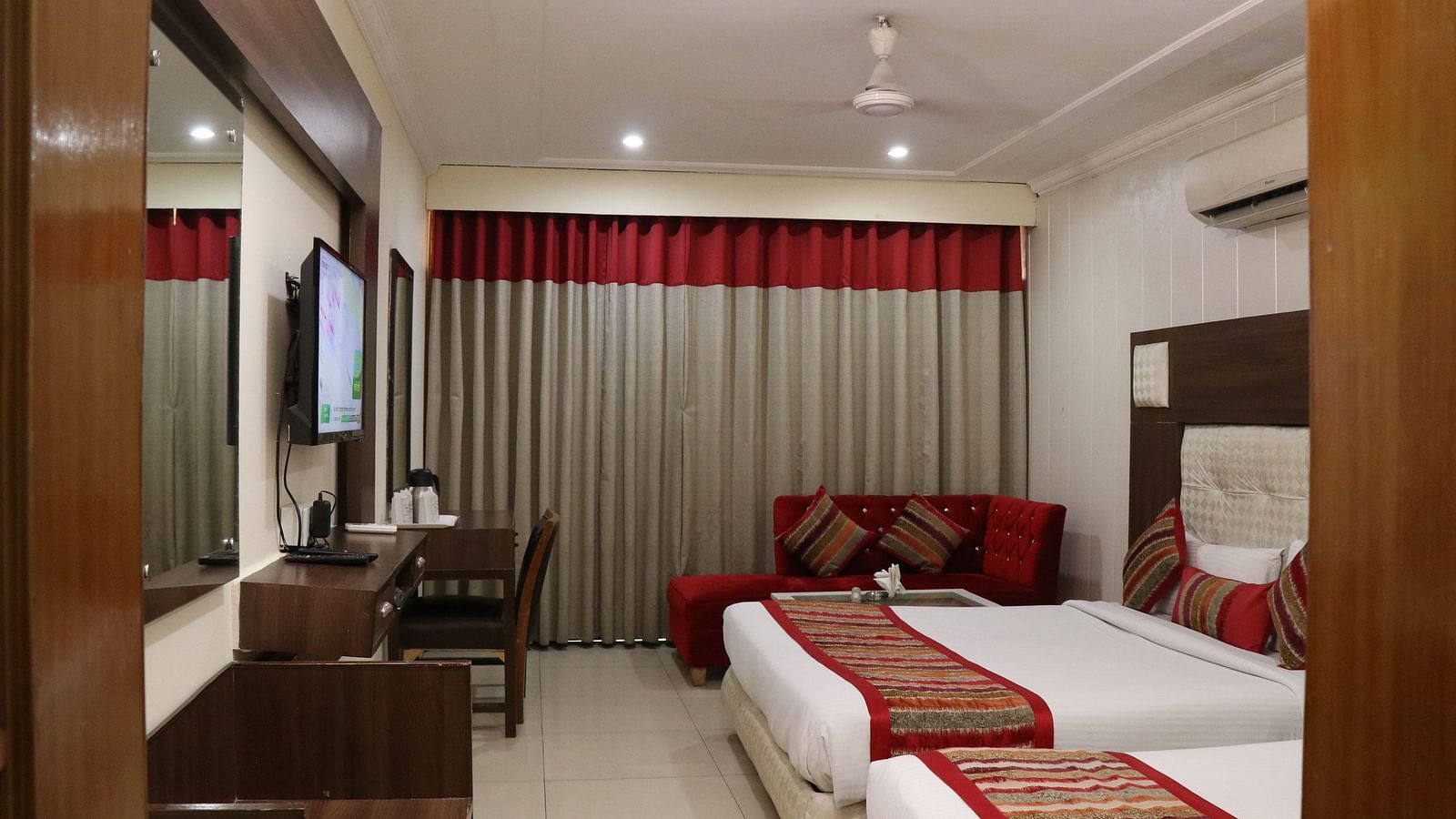 Modern hotel room with two queen size beds, a wall-mounted TV, and a cosy ambience - Hotel Diamond Plaza, Chandigarh.