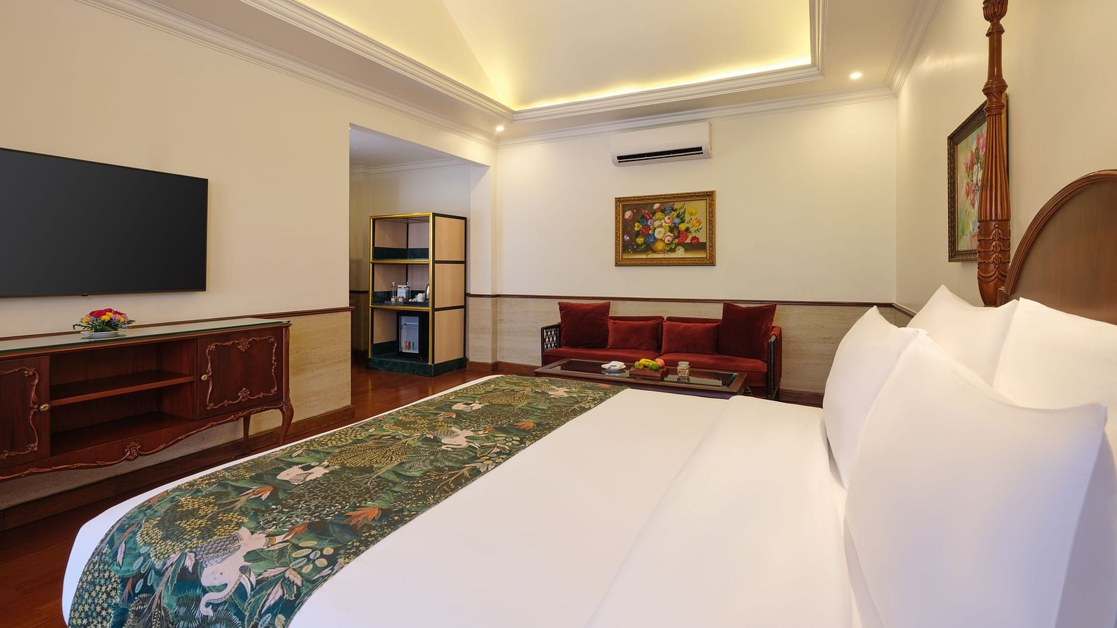 A bedroom with a comfortable bed, TV, sofa, and cupboard at Mayfair Spa Resort and Casino.