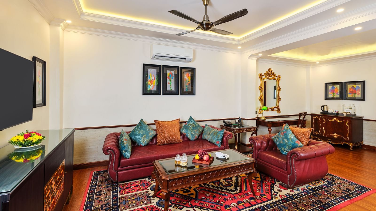 Executive Suite lounge with comfortable sofas, table, cupboard, TV, wall decors and a ceiling fan at Mayfair Spa Resort and casino.