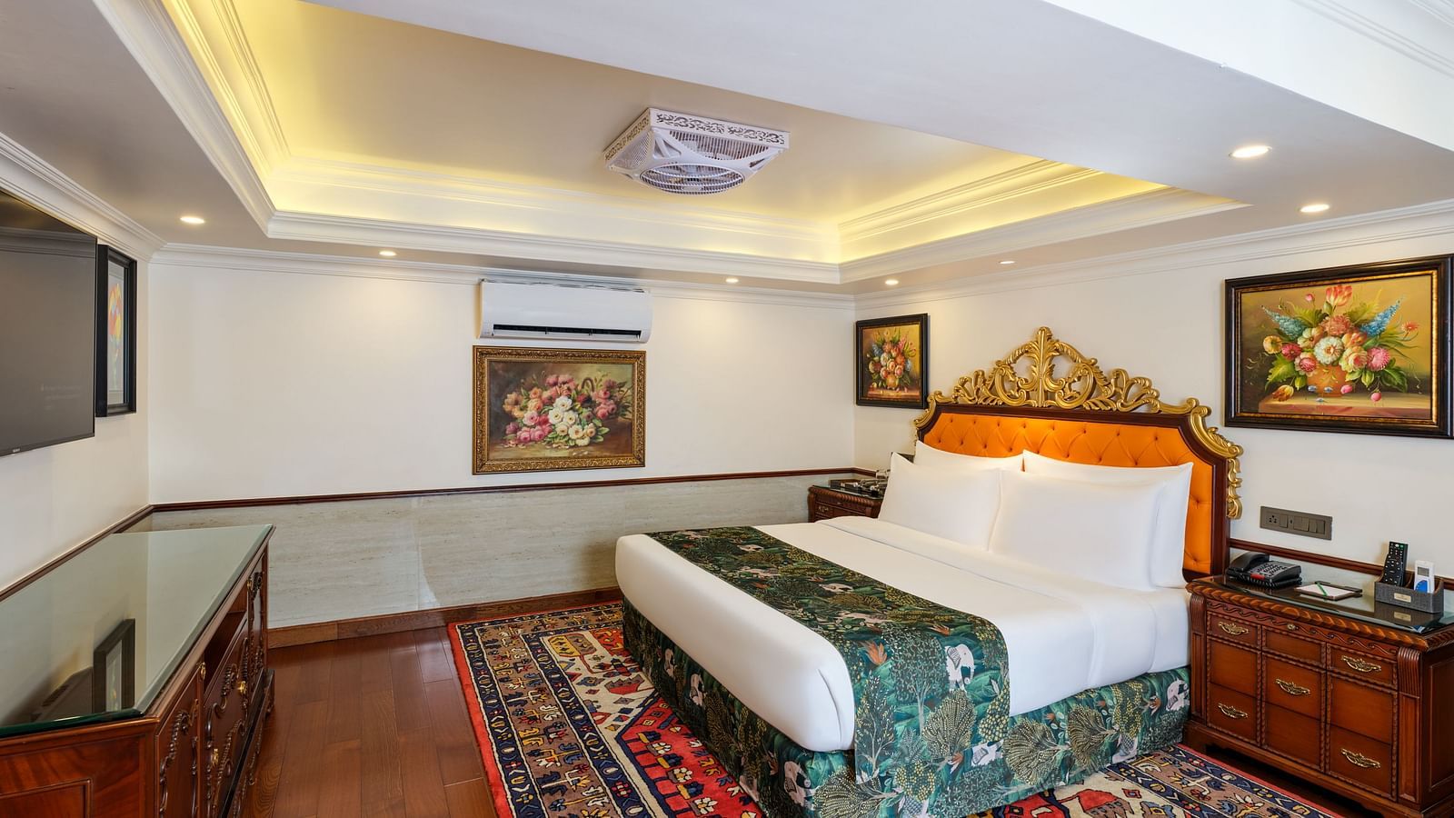Oriental Villa bedroom with a large bed on a decorative rug, paintings on walls and wooden cabinets.