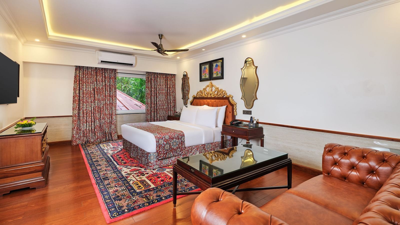 A premium cottage , where a sofa, a table and a grand bed sits beneath a decorative headboard and artwork on the wall with two mirrors.