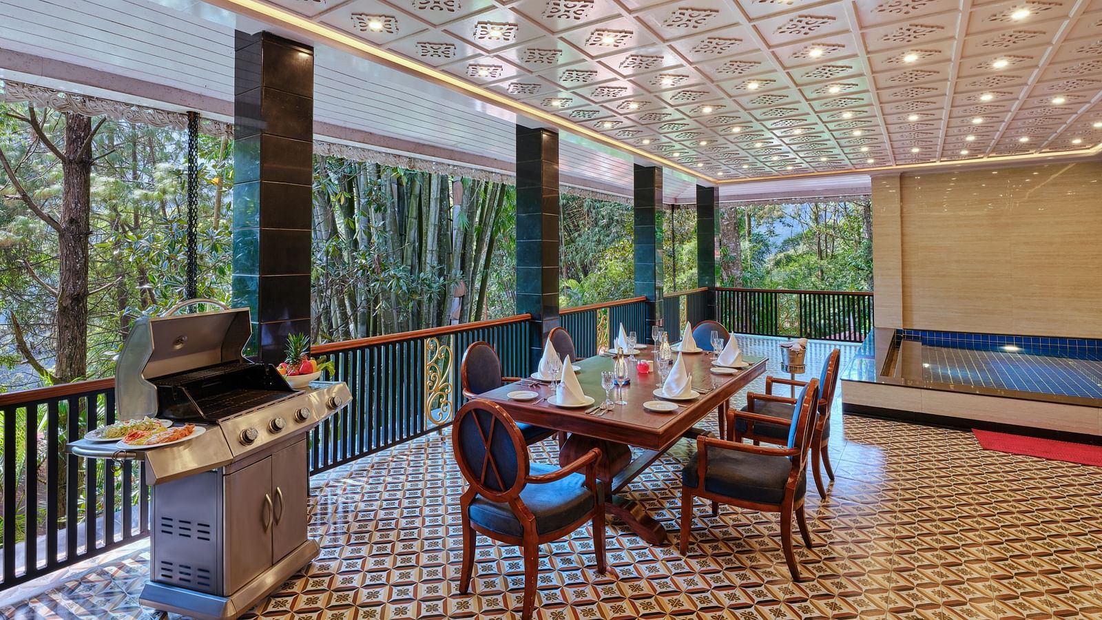 Regent villa outdoor dining area with a barbecue grill, table, chairs and a swimming pool.