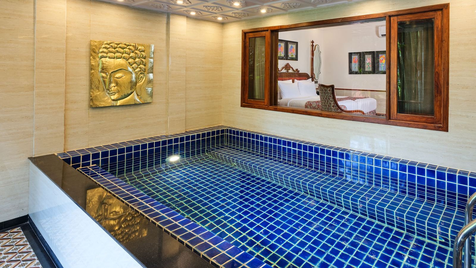 Royal Villa private swimming pool with a gold artwork on the wall. a window through which the bedroom can be seen.