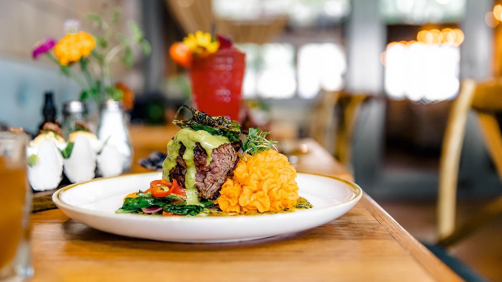 A plated meal and a drink in a modern restaurant setting.- The Grand Hotel & Ballroom, McKinney