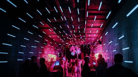 An overview of a night club with red light and people waiting in line
