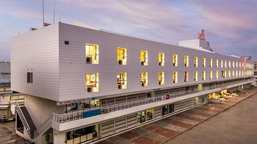 An exterior view at Angel Lords Eco Inn Amreli with many illuminated windows at dusk.