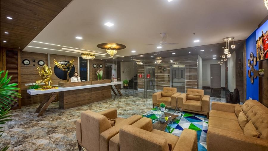 A spacious hotel lobby area with comfortable seating arrangements, tables, and decorative lighting at Angel Lords Eco Inn Amreli.