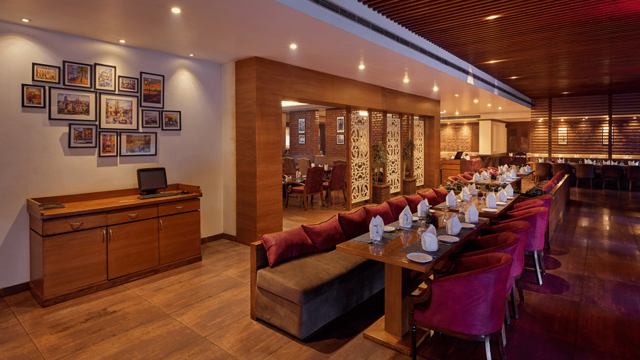 Image of a restaurant interior featuring plush seating, warm lighting, and a collection of framed photos