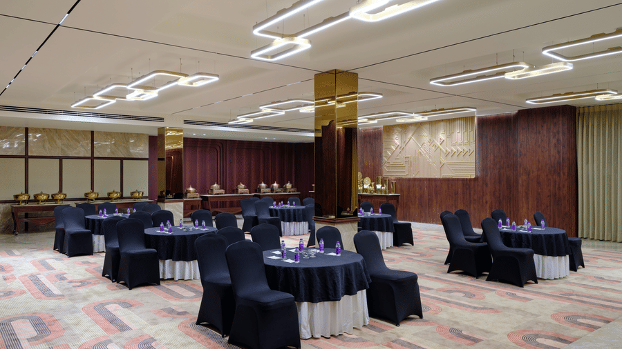 Image of a banquet hall decorated banquet hall with warm lighting, white and blue chairs, and patterned carpet | Best Western Country Woods Hotels and Resorts