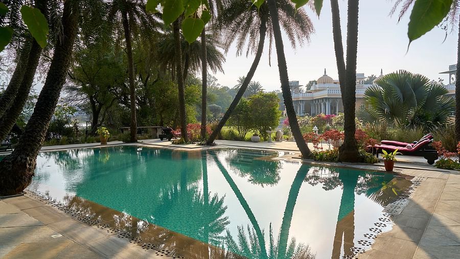 an image of a swimming pool surrounded by palm trees at dev shree, deogarh