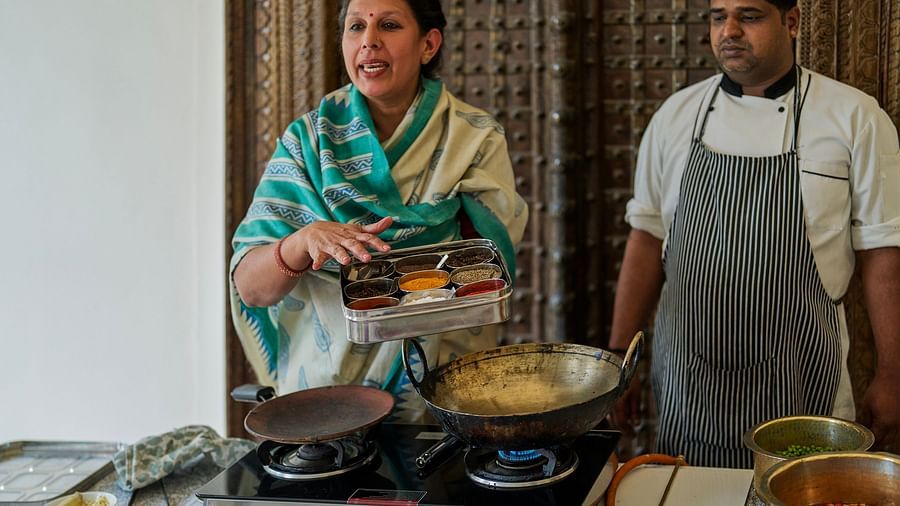 image of a lady explaining the spices in the ox while the other chef is supervising the process at dev shree, deogarh