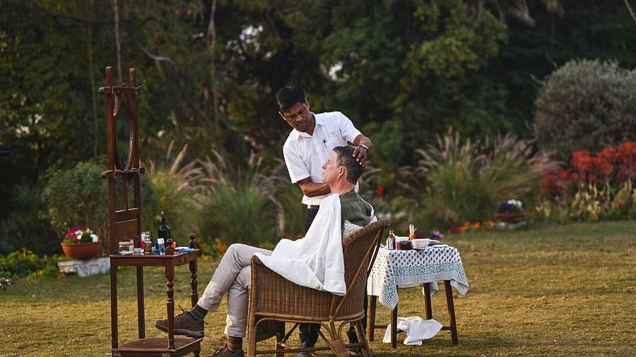 image of a middle aged man getting his beard shaved in a lawn at dev shree, deogarh