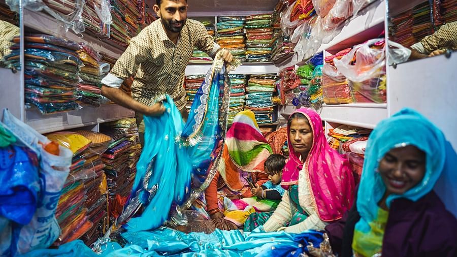 image of a man selling traditional rajasthani sarees in a shop to local women