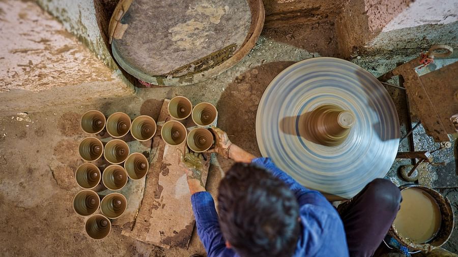 image of a person engaged in pottery where he places the freshly made clay pot on a platform with the other pots