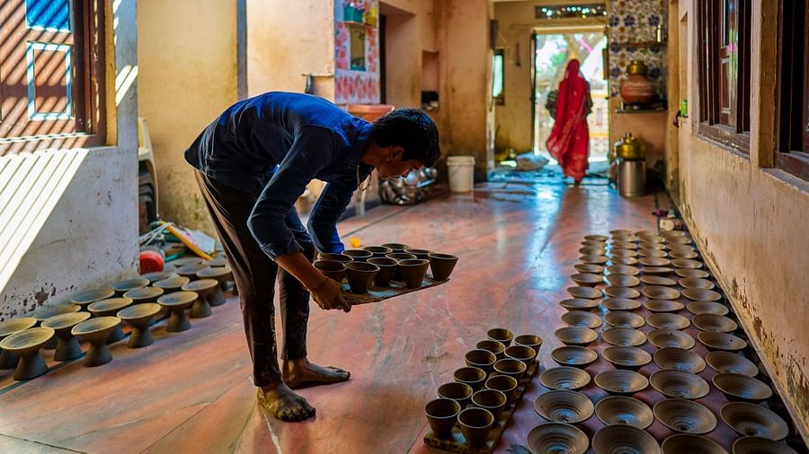 image of a young man lining up raw clay pots inside a room for them to dry