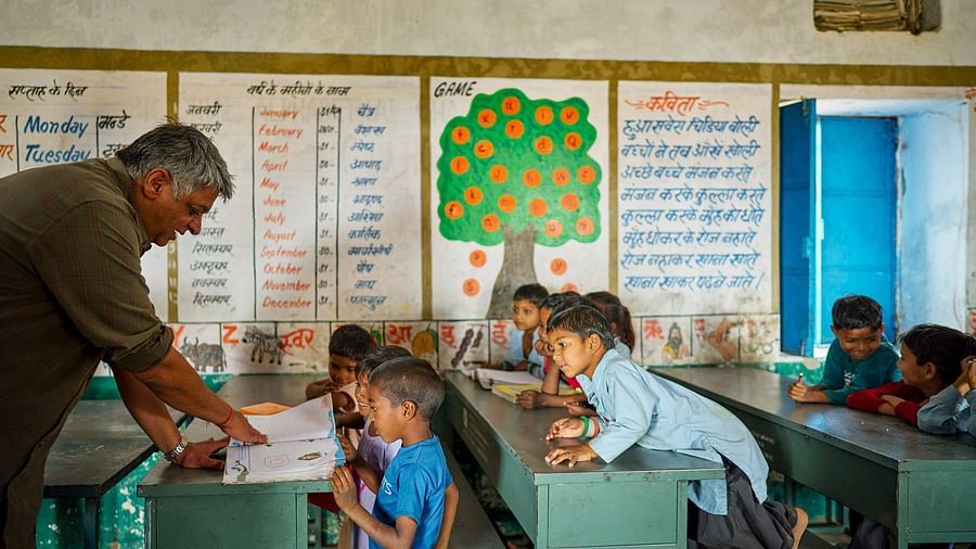 image of an old man teaching the children through a textbook at deogarh