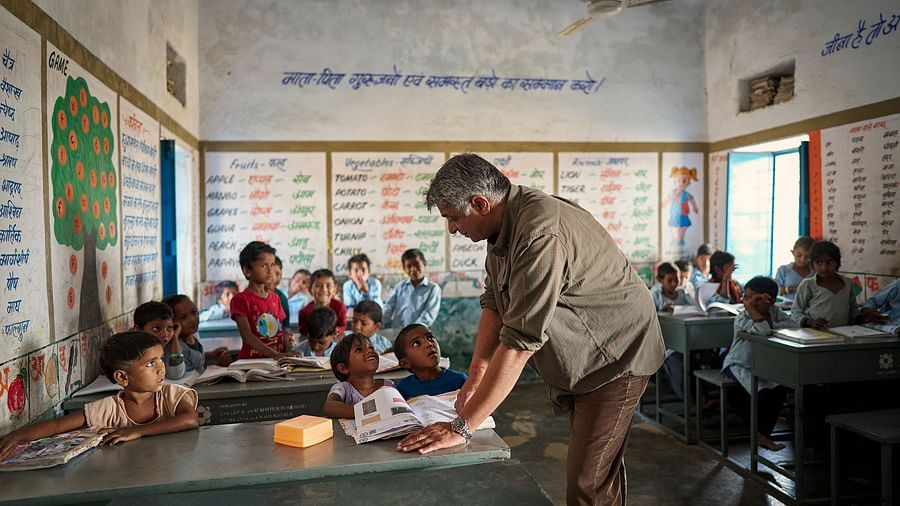 image of an old man teaching students in a government school at deogarh