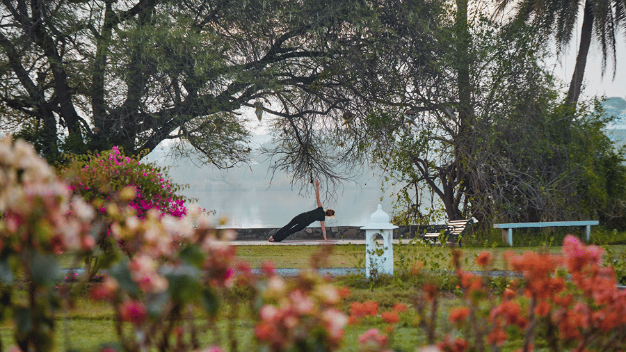 A person practising yoga in a flower garden at Dev Shree, Deogarh, a peaceful retreat near Udaipur in winter.