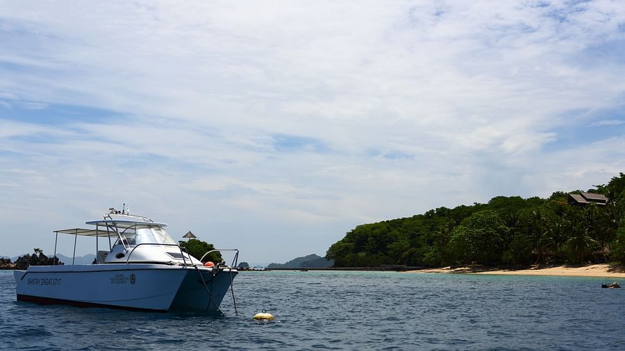 Speedboat anchored in calm blue waters with lush island backdrop.