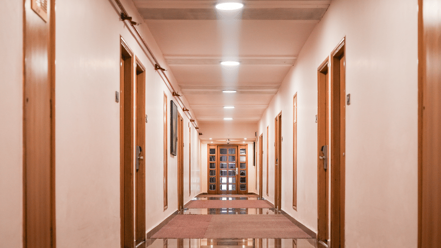 Polished hallway with marble floor, guest room doors, and ceiling lights at Infiniti Hotel, Indore.
