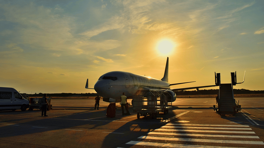 Airplane parked on a runway featuring a staircase attached at sunset.