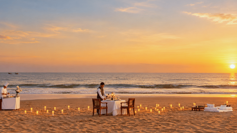 Private dining experience on the beach at sunset with a server preparing a candlelit table at MAYFAIR Palm Beach Resort, Gopalpur-on-Sea.   