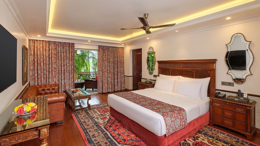 Premium Cottage featuring a wooden bed with white bedding, a decorative rug, a ceiling fan, framed pictures, and a window with bamboo trees, complemented by a patterned curtain