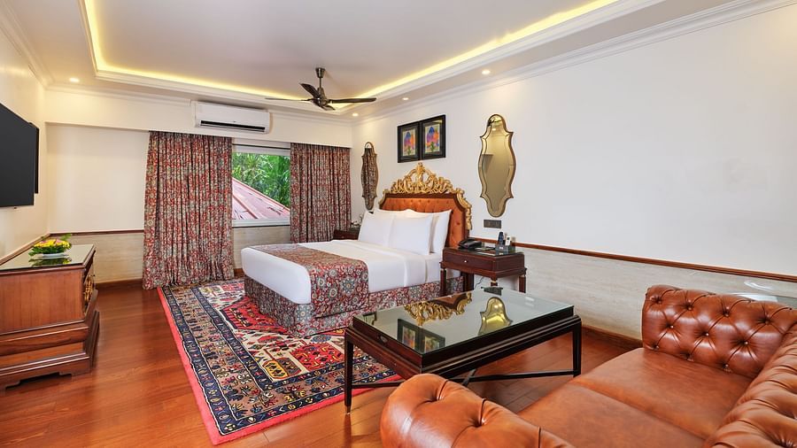 a premium cottage , where a sofa, a table and a grand bed sits beneath a decorative headboard and artwork on the wall with two mirrors