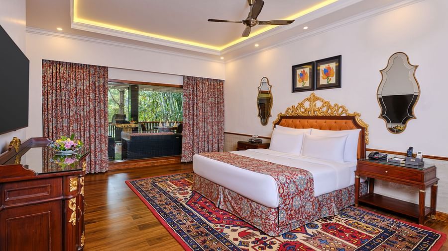 a luxurious regent villa, where a table and a grand bed sits beneath a decorative headboard and artwork on the wall with two mirrors. 