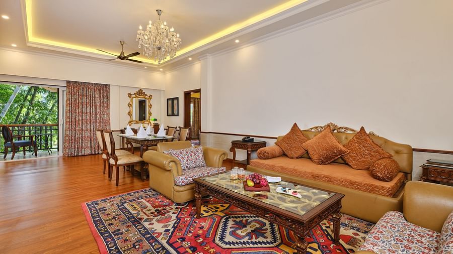 beautiful interior seating area of  suite with a table, chairs, sofas, chandelier,  and a balcony overlooking greenery