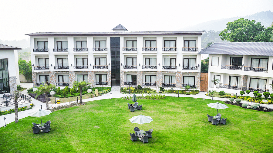 Aerial view of the resort's well-maintained lawn with outdoor seating areas, surrounded by modern guest rooms - Shervani Pebbles & Pines, Corbett