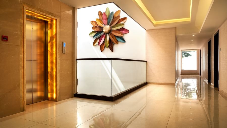 Corridoor view a The Hamuse Hotel, Kodaikanal with a lift and an interior floral design being projected on the wall.