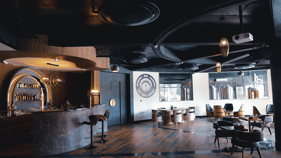 Rhythm & Brews featuring a a bar area with a unique ceiling design and patrons seated at tables at The Qualia Resort Club & Brewery, Udaipur.