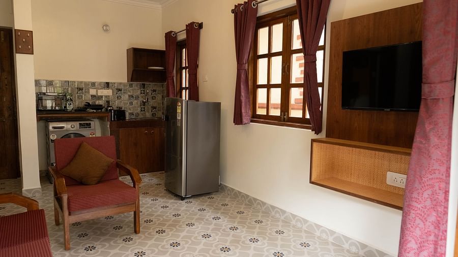Image of a seating area with a television in front and kitchen with fridge at 1 bhk Executive Studio Apartment, Vistar Holidays, Goa.