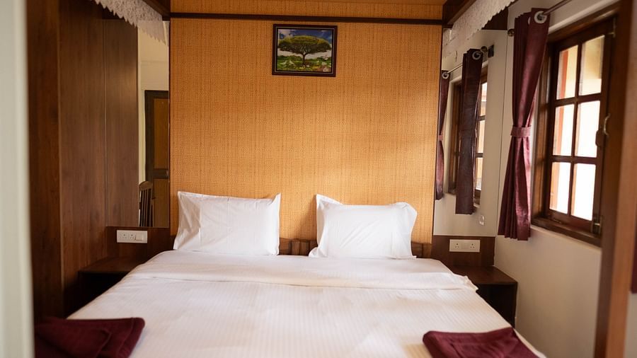Image of a bed with a frame above it and windows on the side at 2 bhk Studio Apartment, Vistar Holidays, Goa.