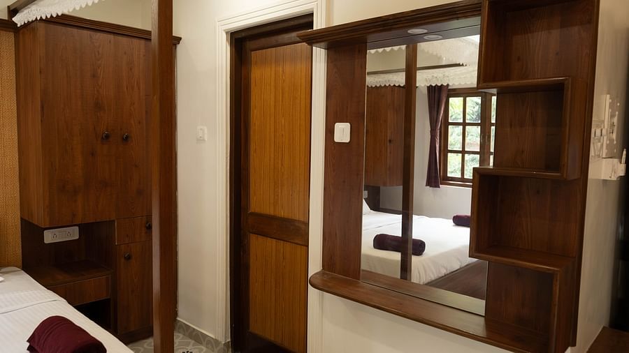 Image of a mirror mounted on the wall with wooden frame at Vistar Holidays, Goa.