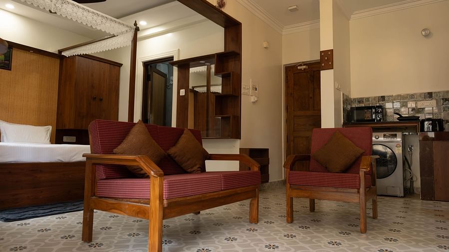 Image of a seating area with sofas and a bed behind the bed at Vistar Holidays, Goa.