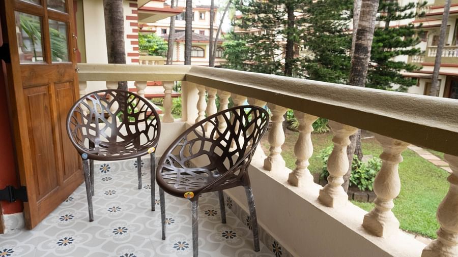 Image of a balcony with two chairs where the view of the balcony overlooks the surrounding areas at the Vistar Holidays, Goa.