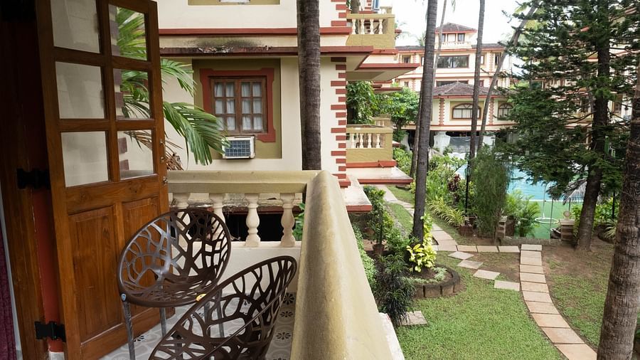Image of a balcony with two chiars and trees in the background at the Vistar Holidays, Goa.
