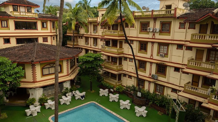 Facade of  Vistar Holidays, Goa with chairs placed besides the pool.