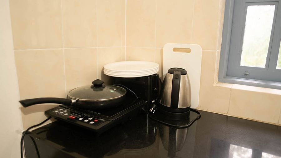 Image of an induction with a pan on top of it and a water kettle beside it at Vistar Holidays, Goa.