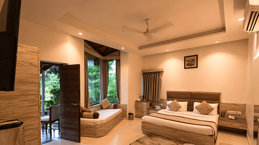 A brightly lit resort suite featuring a double bed, soft rug, and a cozy bay window daybed - Wood Castle Spa & Resort, Jim Corbett