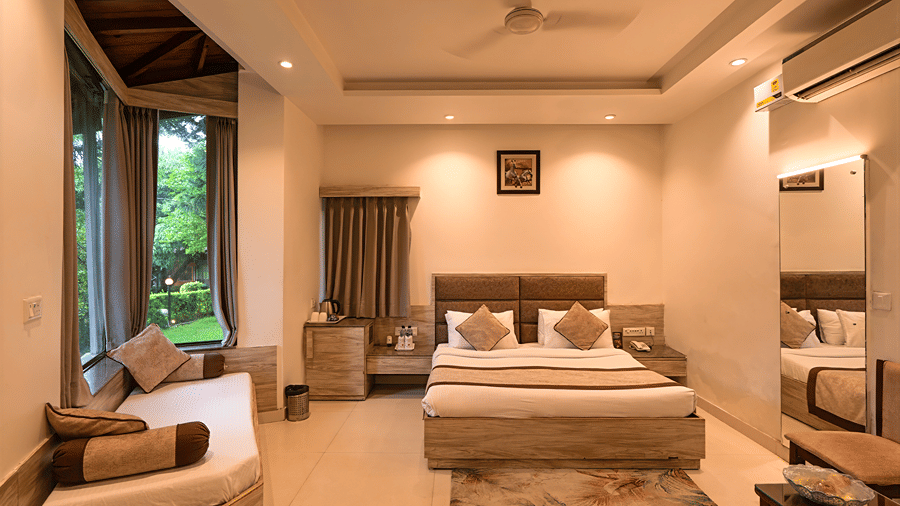 A wide-angle view of a luxury suite featuring a double bed, seating area, vanity mirror, and window seating - Wood Castle Spa & Resort, Jim Corbett