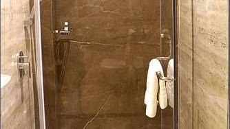 Image a washroom with a shower area and a towel hanging on the door at Calux Grand Inn, Calangute.