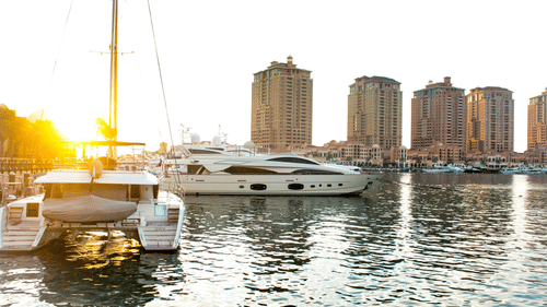 Yachts parked in the bay with a few buildings in the backdrop at sunset