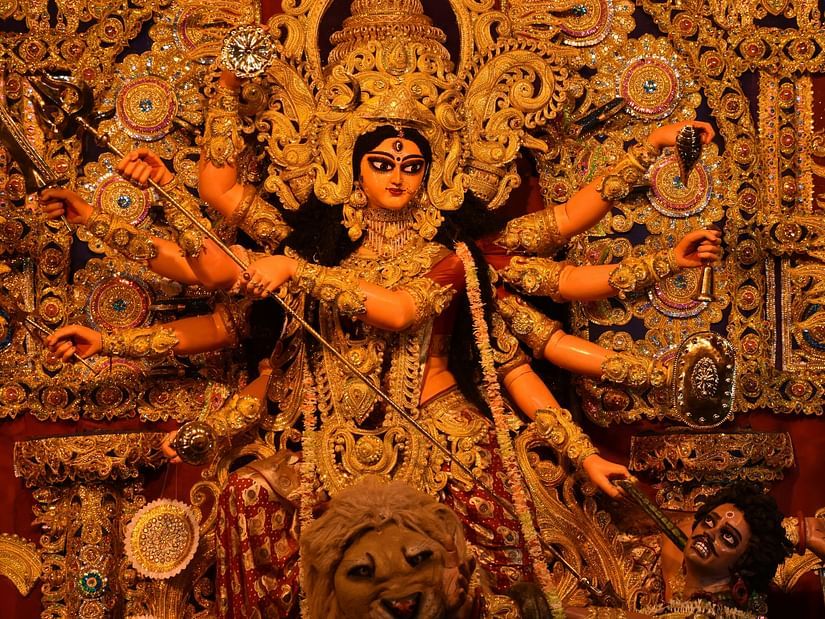 A close up shot of the idol of Goddess Durga with her numerous arms inside a temple.