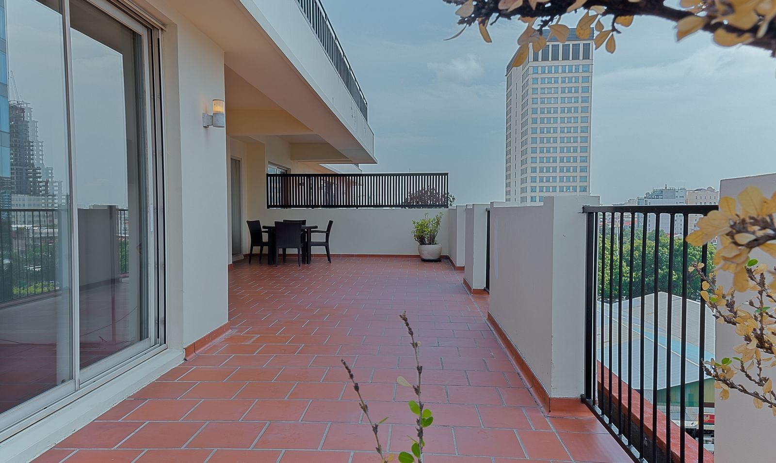 An outdoor patio area with a red tiled floor and a railing | Penthouse | Central Mansions, Phnom Penh