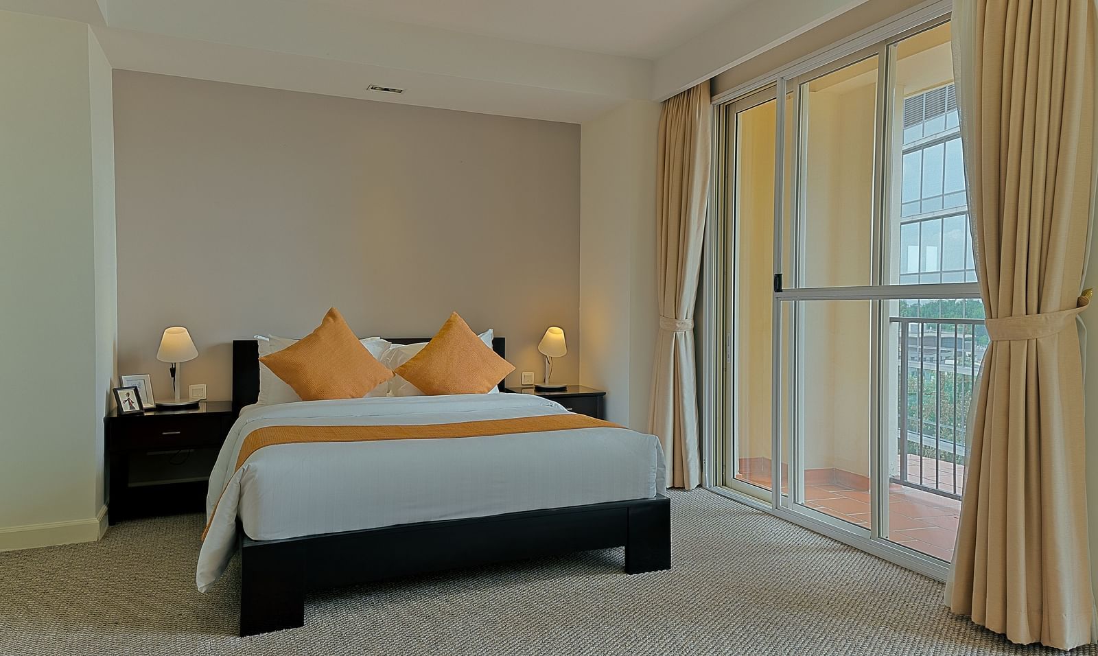 A bedroom with a bed, nightstand, and curtains | Penthouse | Central Mansions, Phnom Penh