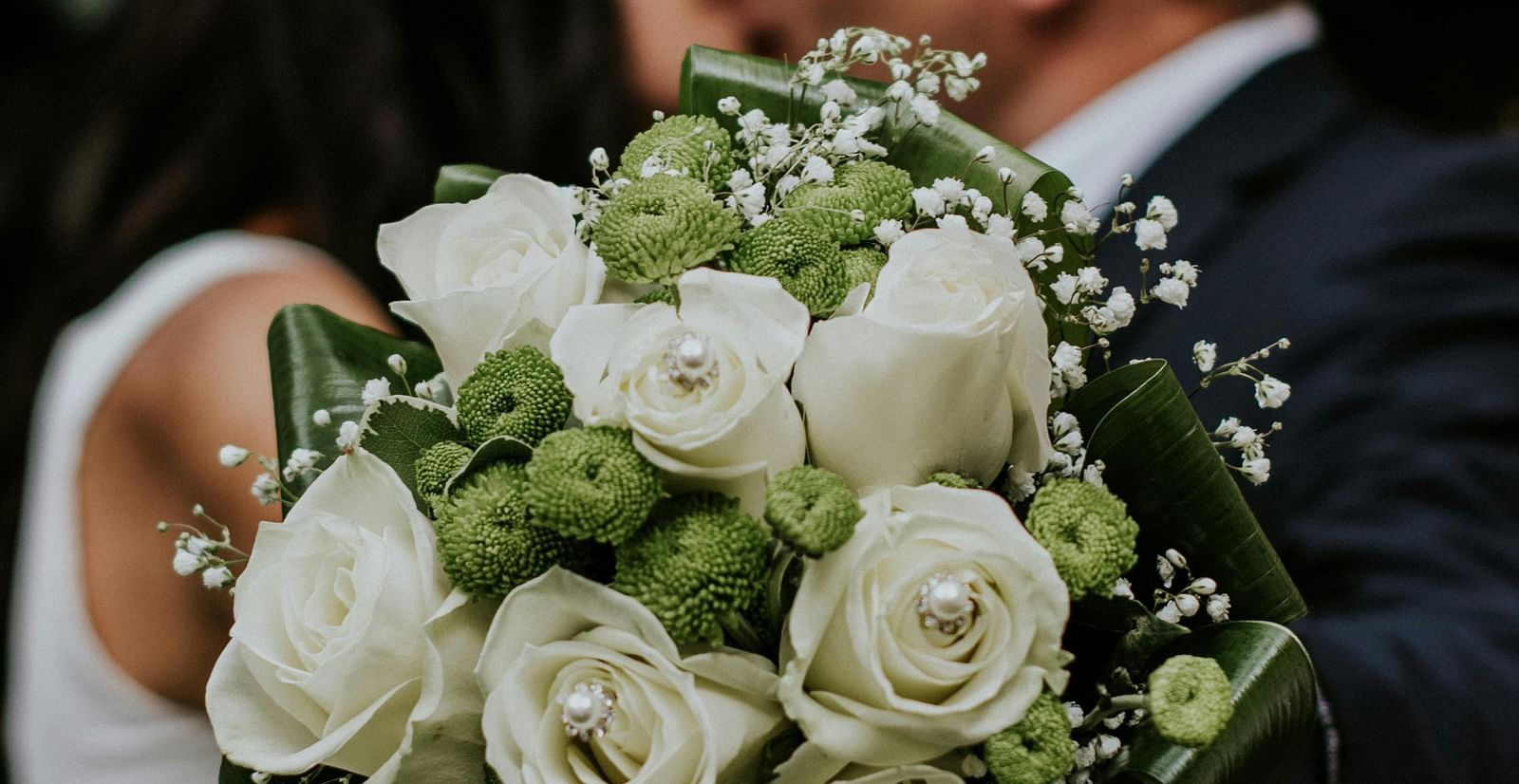 A couple posing with a bouquet of white roses for a photoshoot